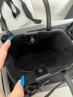 Dark tote bag interior view with logo plaque and inner pocket strap detail