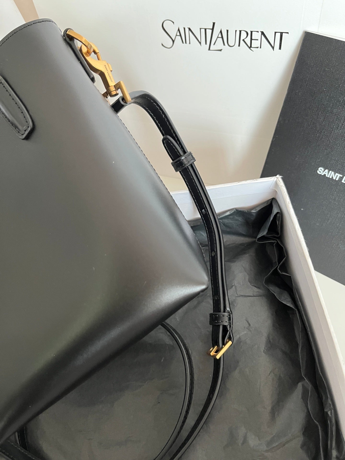 Dark gray leather tote bag showing side strap and gold clasp hardware