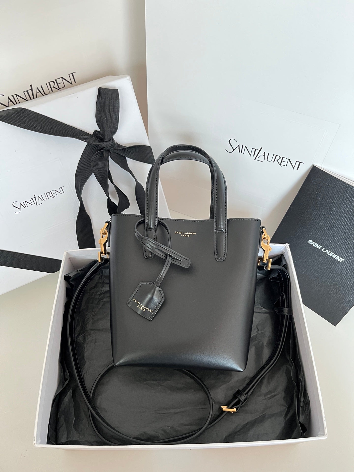 YSL dark gray leather tote bag with top handles, bow charm, and gold hardware
