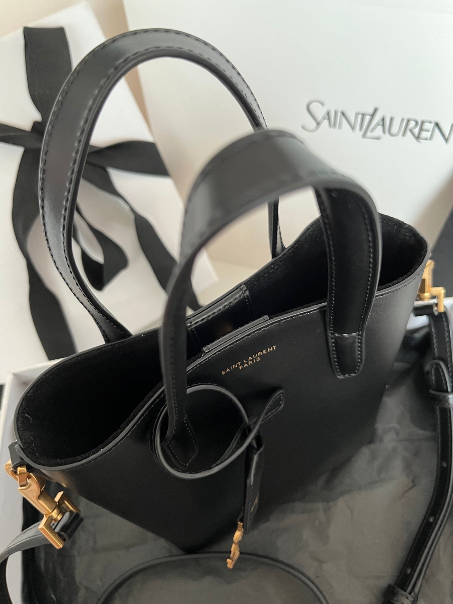 Dark gray leather tote bag with wide handles, internal strap detail, and gold hardware