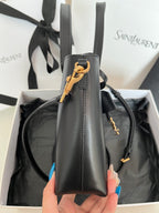 Dark gray leather tote bag with vertical side view and gold charm hardware