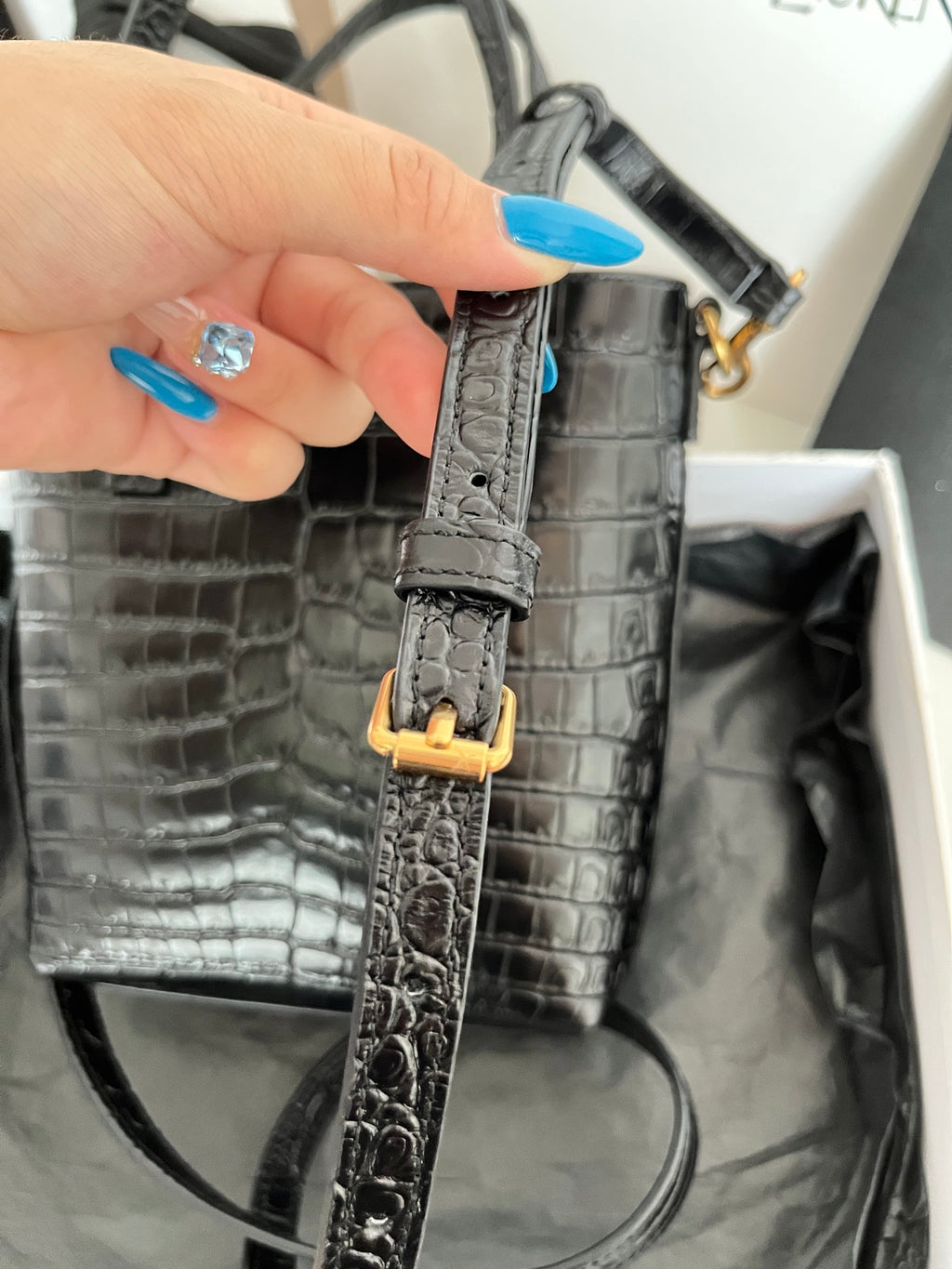Black croc-embossed leather shoulder strap with gold buckle hardware