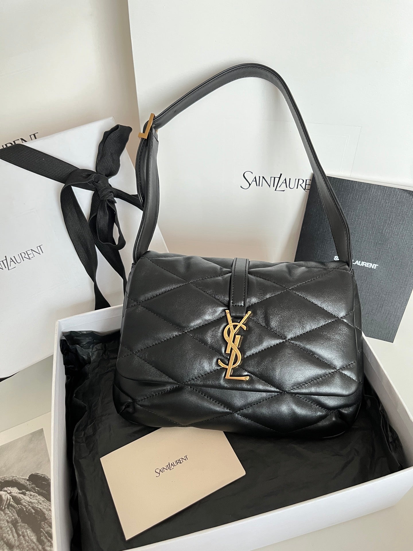 Quilted dark leather shoulder bag with structured top handles and gold YSL monogram clasp