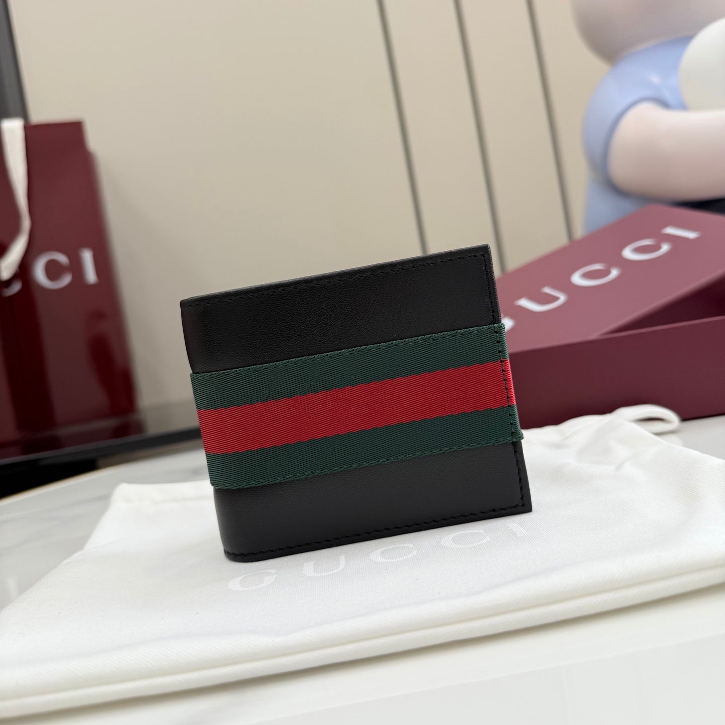 Gucci small leather wallet, black with green-red-green web stripe on front.