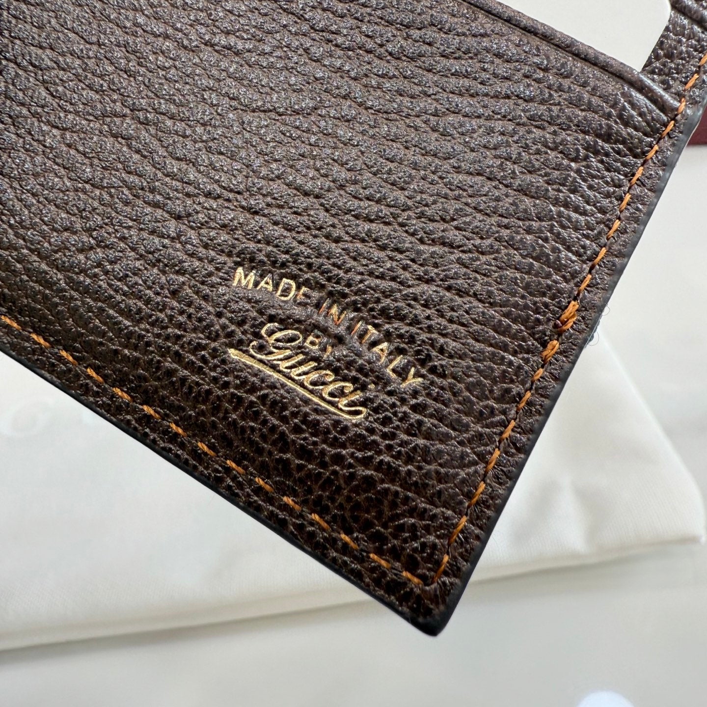Brown Gucci leather wallet label reading "MADE IN ITALY" and "Gucci"