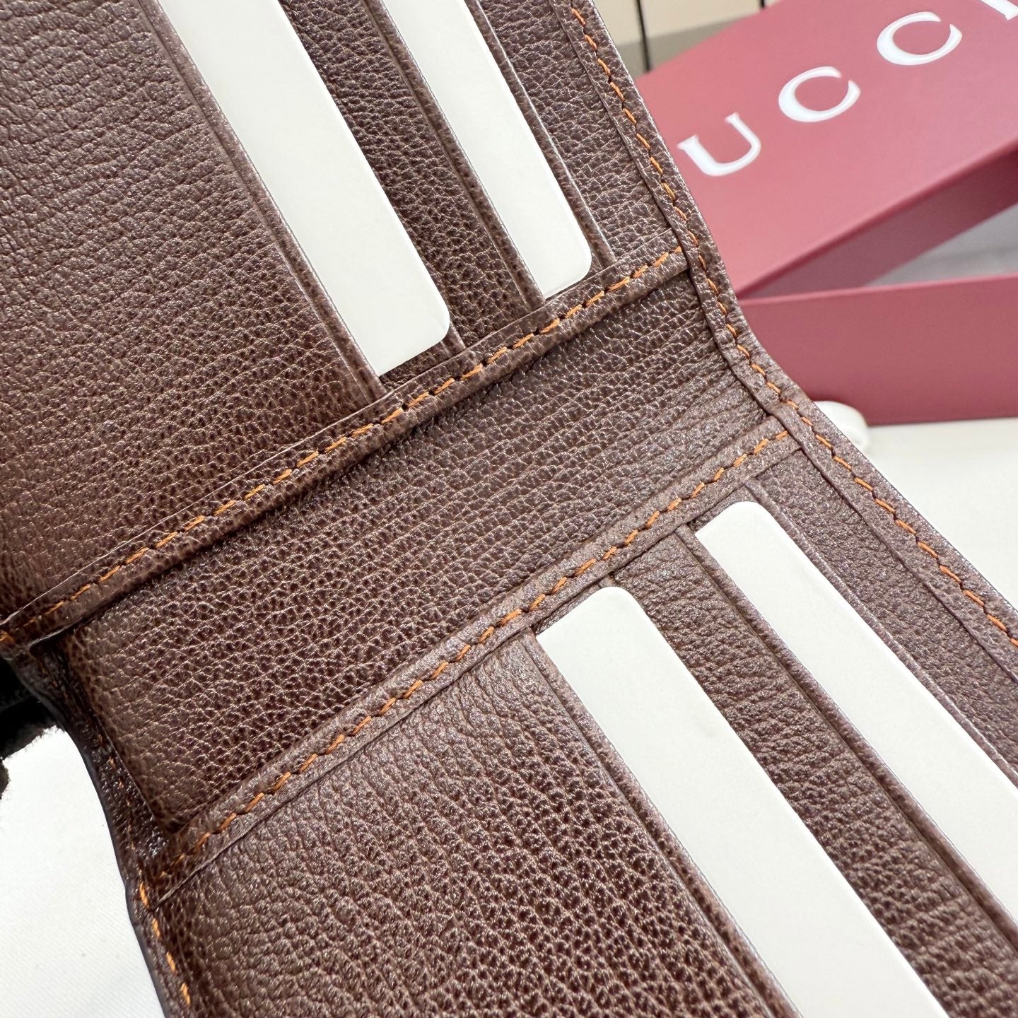 Gucci brown leather card wallet close-up with white stripe tabs and stitching