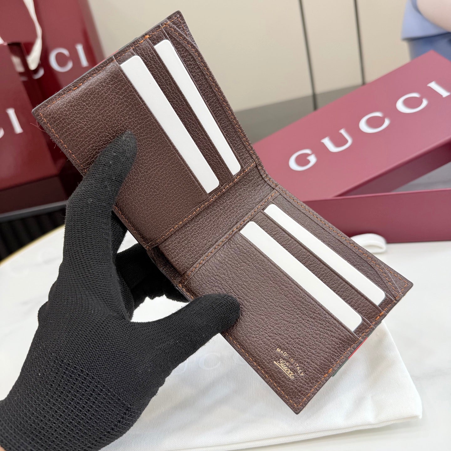 Gucci small wallet with brown leather exterior and white stripe tabs, close view