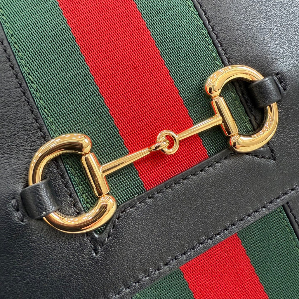 Gold-tone clasp detail on black leather Gucci strap with green and red stripe