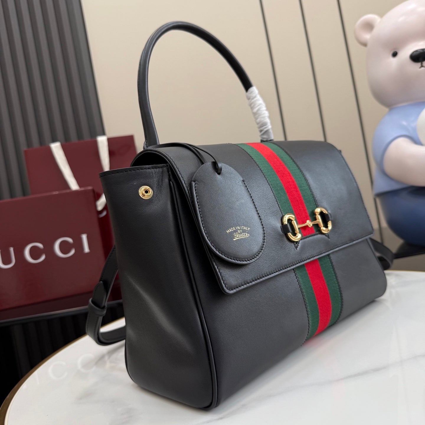 Black leather Gucci tote bag with web stripe and flap, gold-tone hardware
