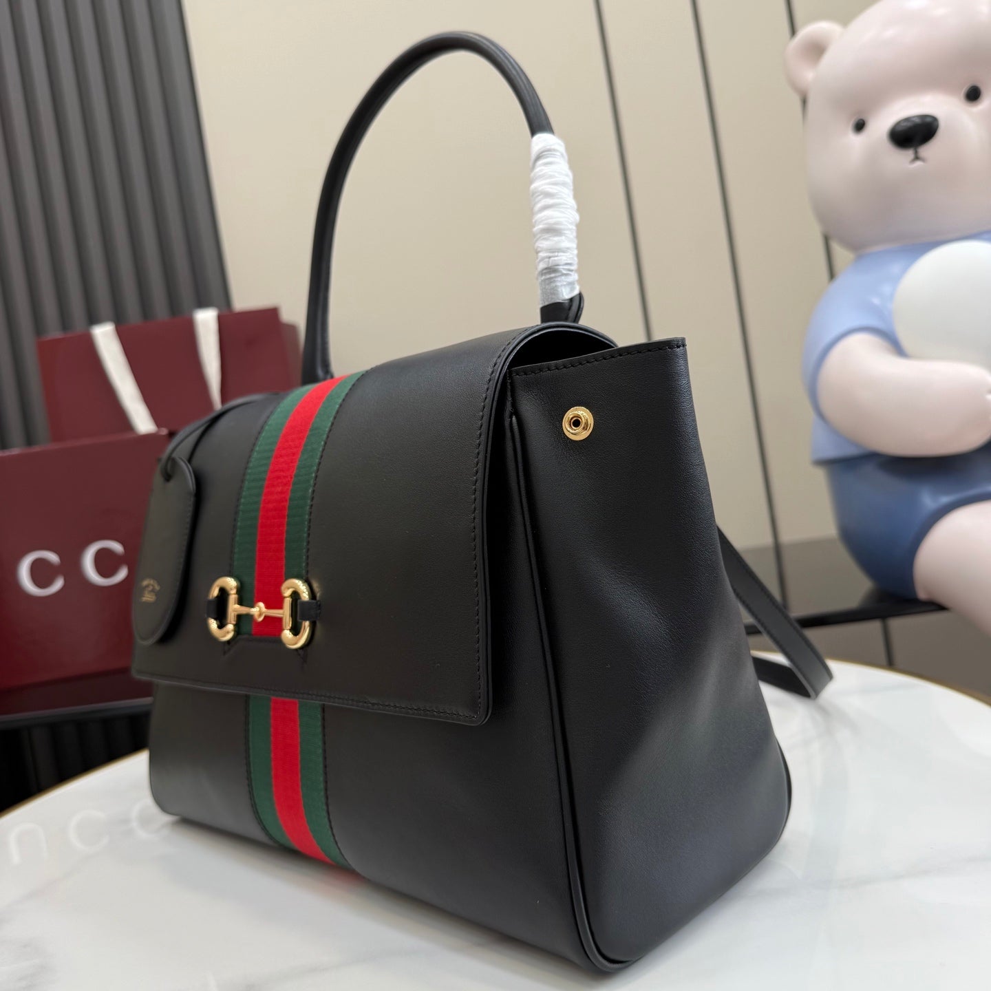 Black leather Gucci tote bag with web stripe, front emblem, and gold hardware