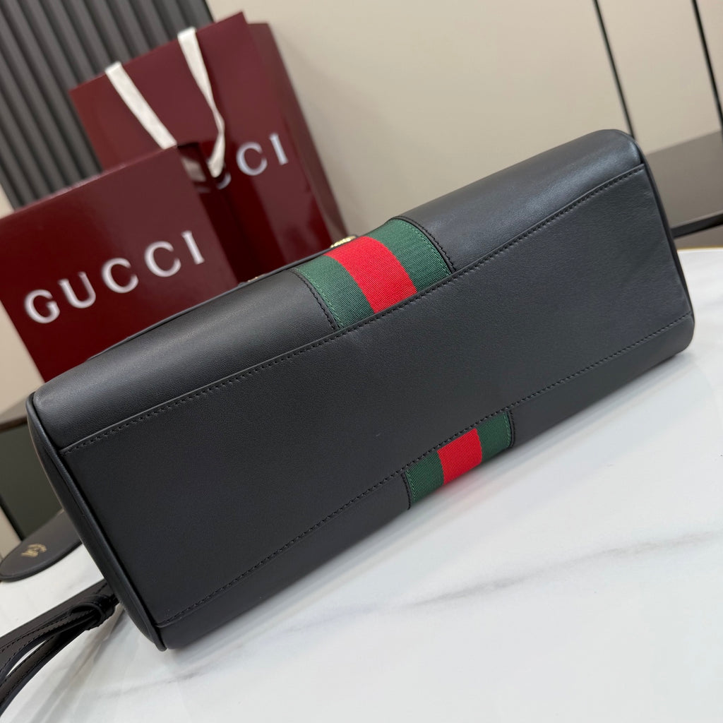 Black leather Gucci bag with green and red web stripe on top flap