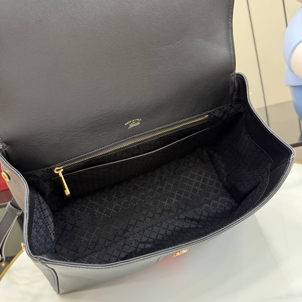 Black leather Gucci bag interior with dark patterned lining and zip pocket