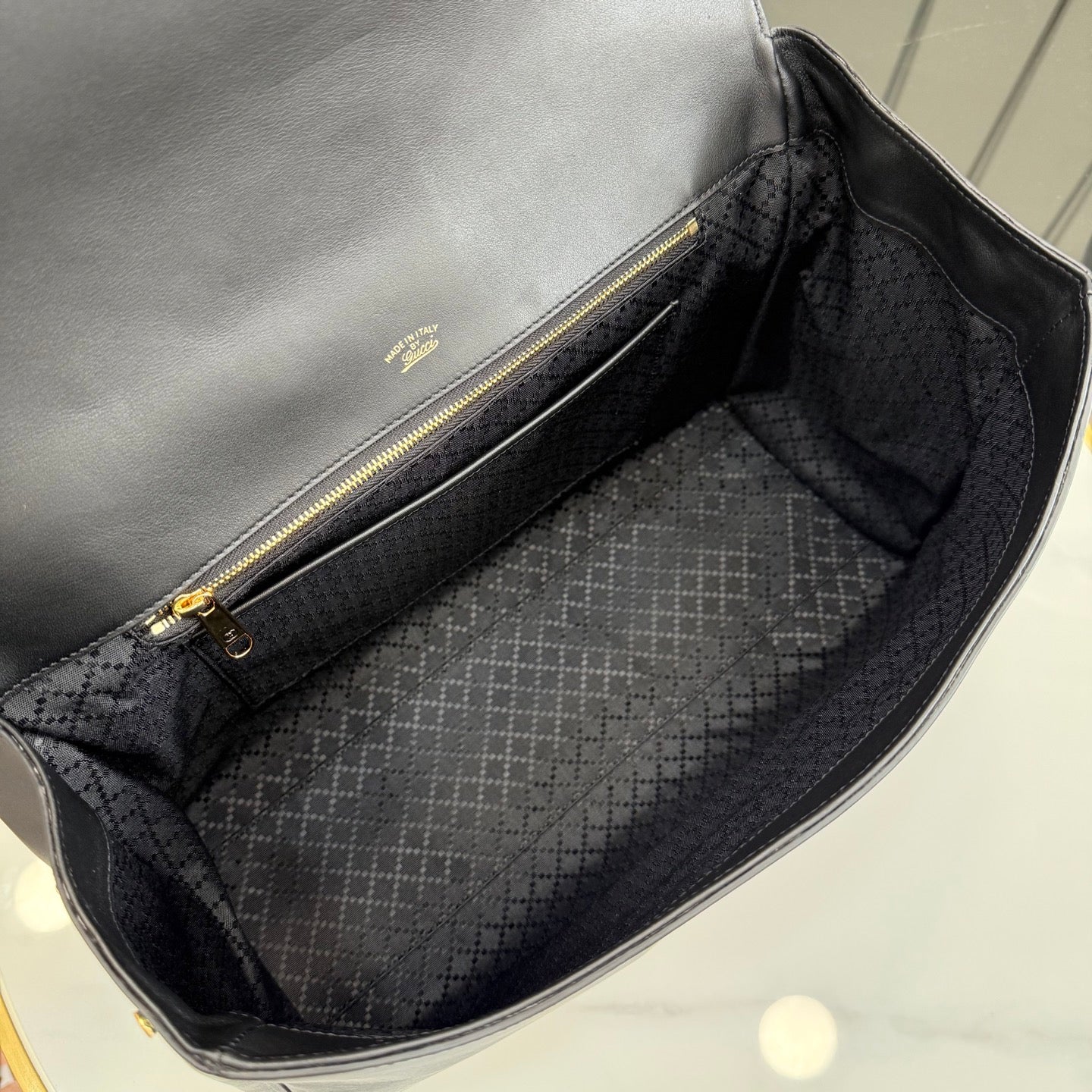 Gucci bag interior with fabric lining and gold zipper pull, viewed from inside