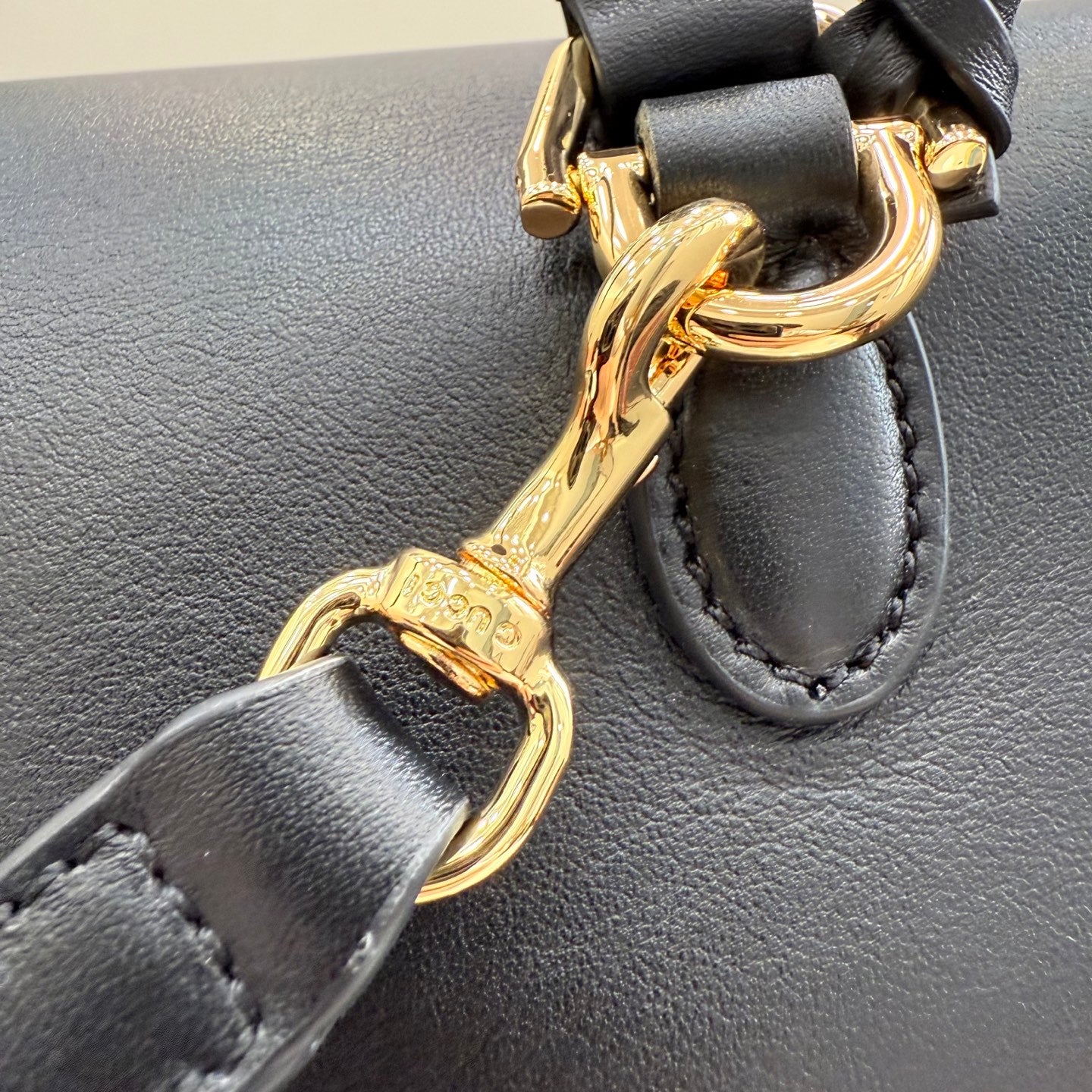 Gucci bag strap hardware with gold-tone buckle and ring on dark leather