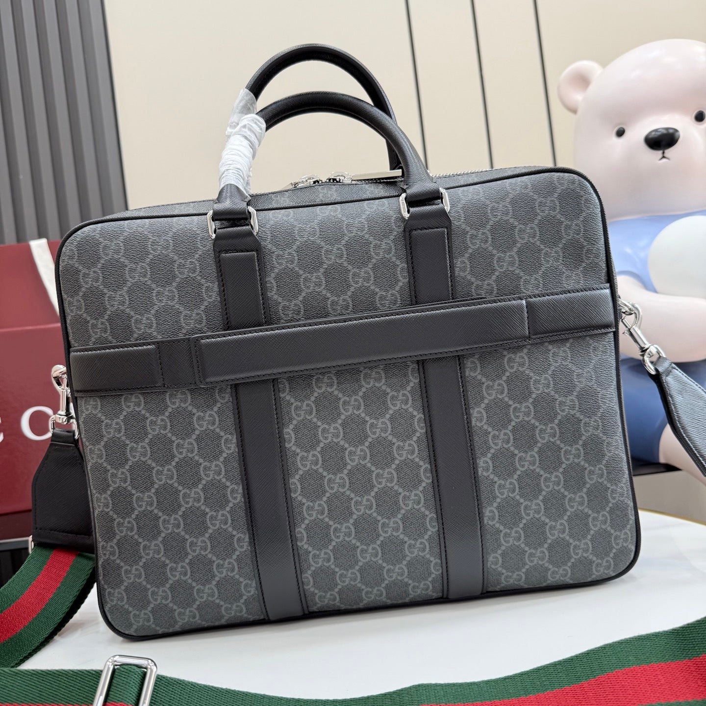 GG monogram top-handle bag with wide front strap and structured dark leather trim.
