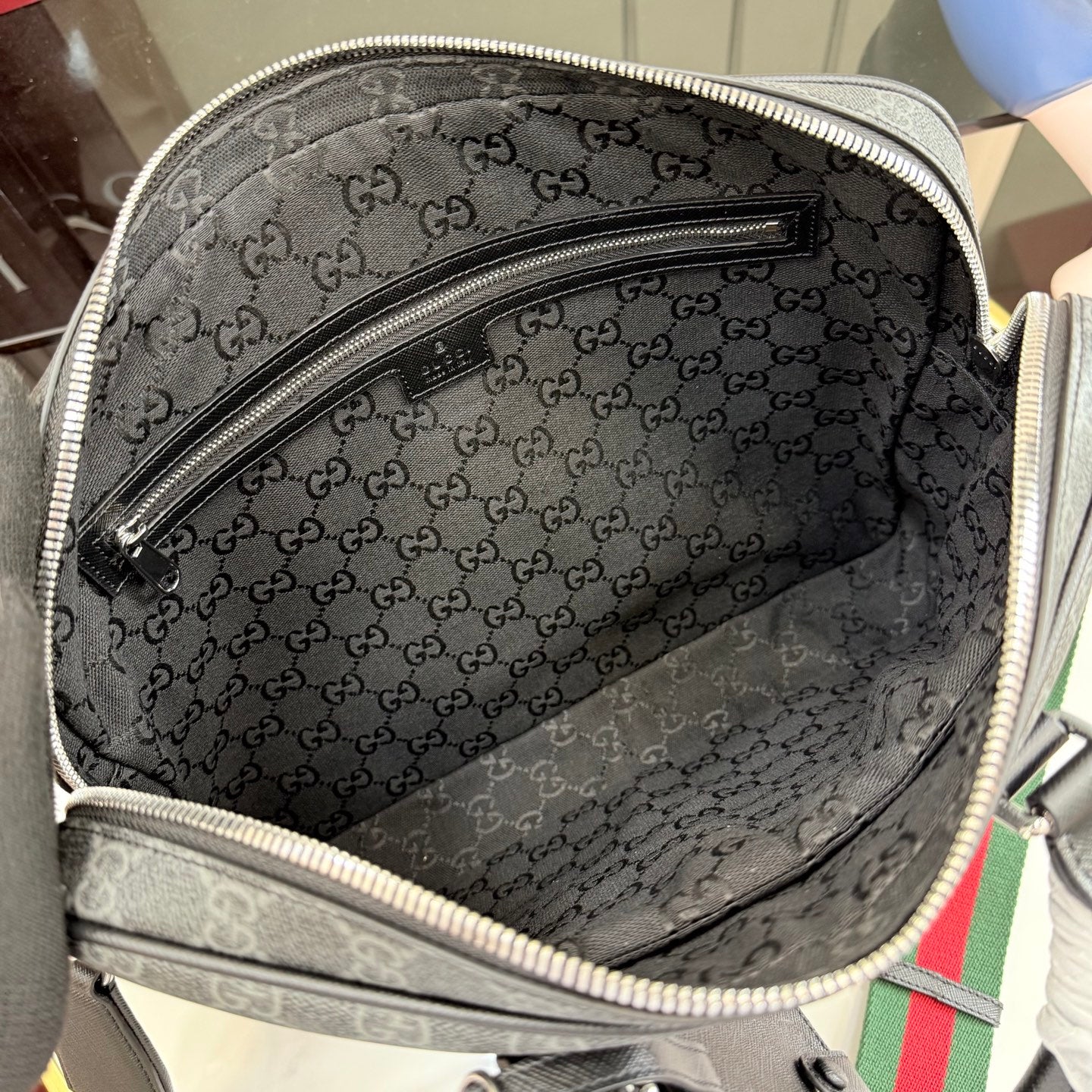 Interior of GG monogram bag with zippered pocket and dark lining.