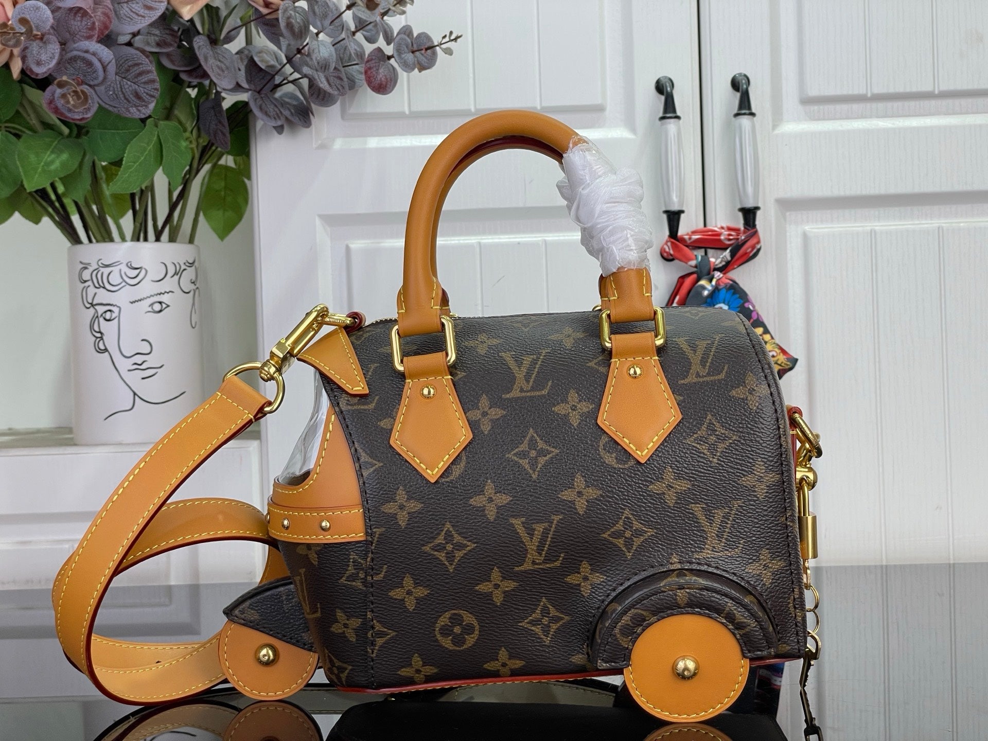 Louis Vuitton monogram handbag with tan shoulder strap and gold hardware, side view
