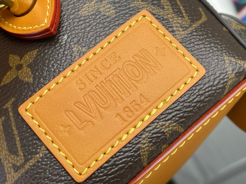 Tan leather nameplate with embossed Louis Vuitton text on monogram canvas bag
