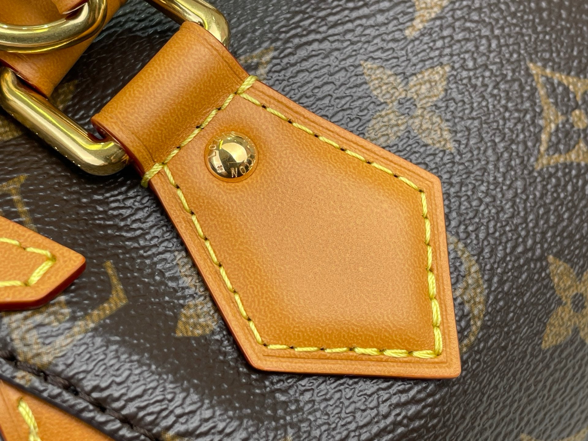 Tan leather luggage tag patch with stitched border on monogram handbag