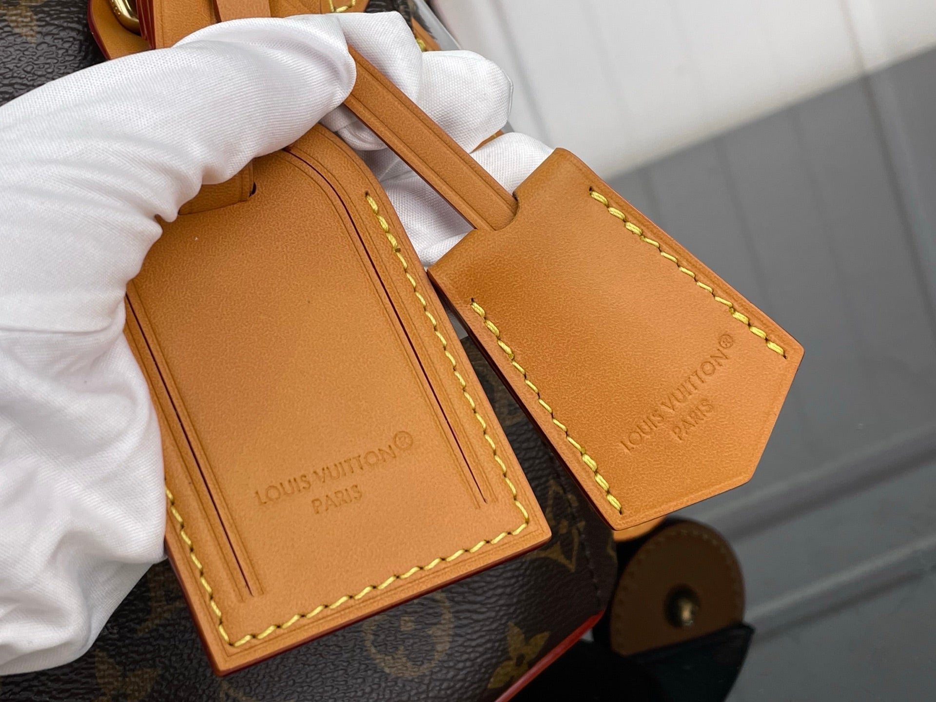 Tan leather handbag strap with stitched edges and embossed logo text
