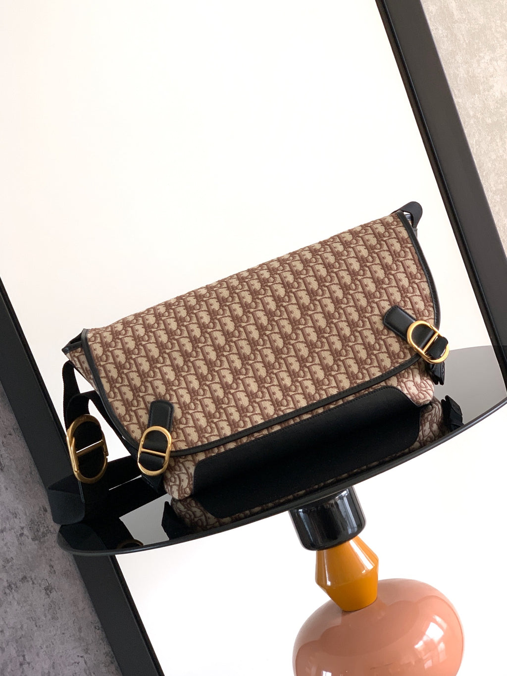Dior bag in beige and brown monogram canvas with black flap and gold hardware.