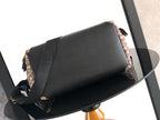Dior bag with black leather flap and beige monogram sides, gold-toned strap hardware.