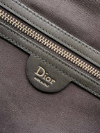 Dior zipper pull and leather pocket on dark fabric bag front