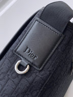 Dior logo leather tab with stitching on dark woven bag strap