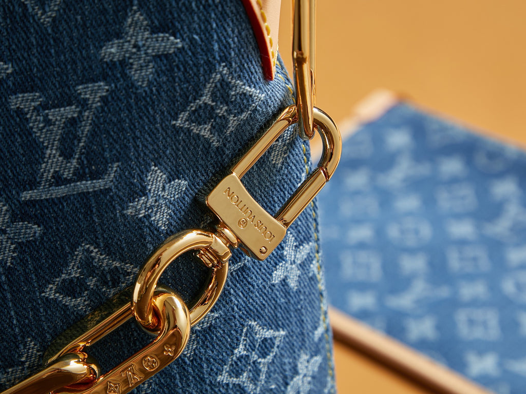 Gold clasp and keyring on blue monogram bag strap with engraved hardware