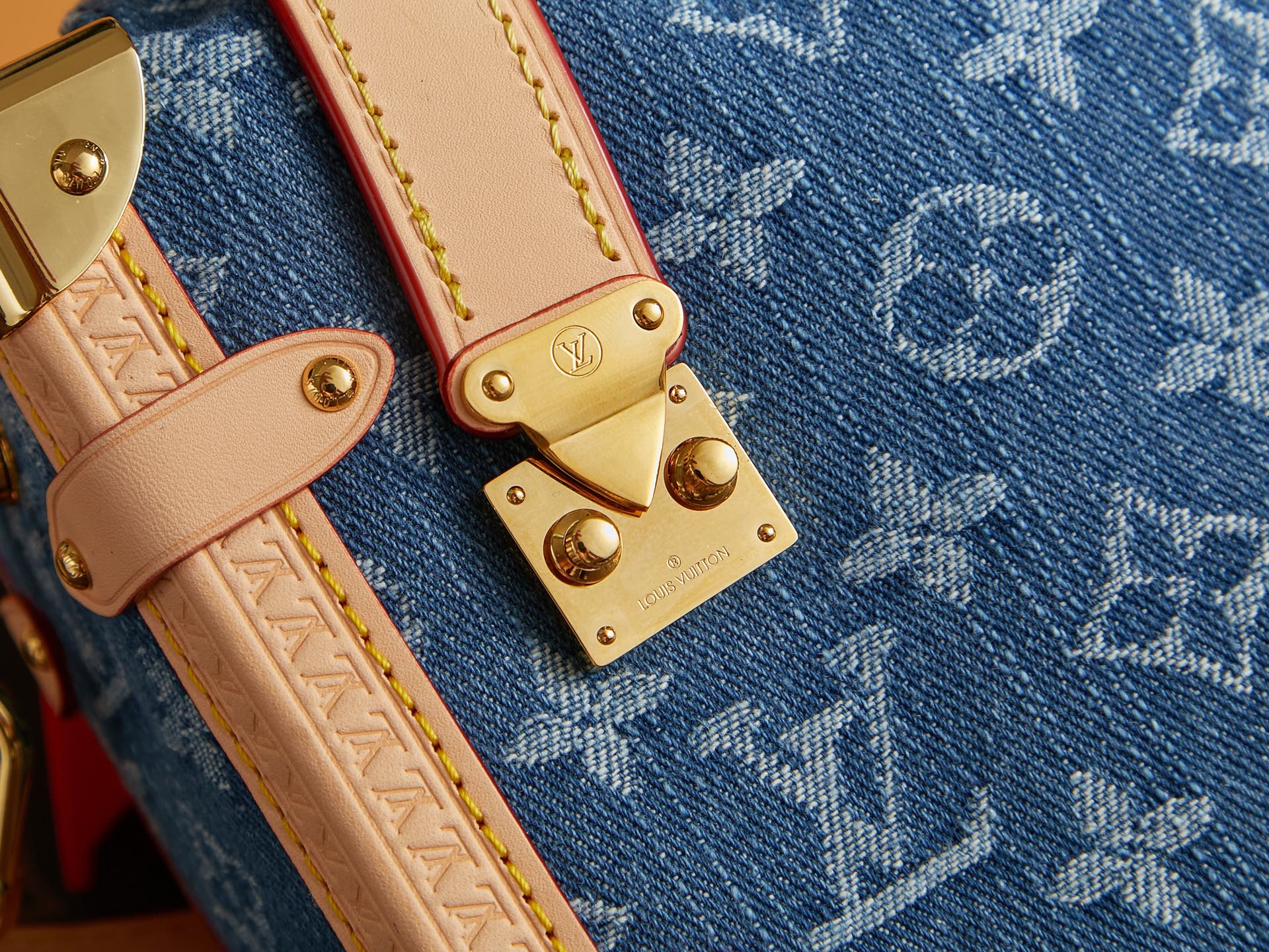 Louis Vuitton blue monogram canvas handbag detail with tan leather strap and gold hardware