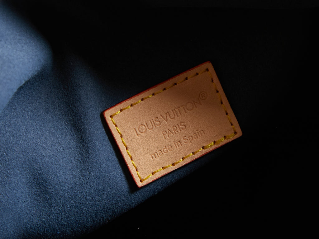 Louis Vuitton interior label on blue fabric lining with tan leather border