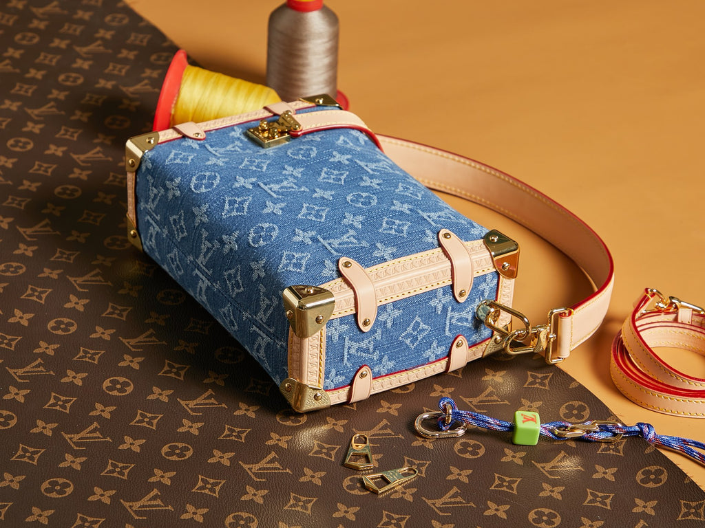 Louis Vuitton handbag with blue monogram canvas, tan leather straps, and gold hardware