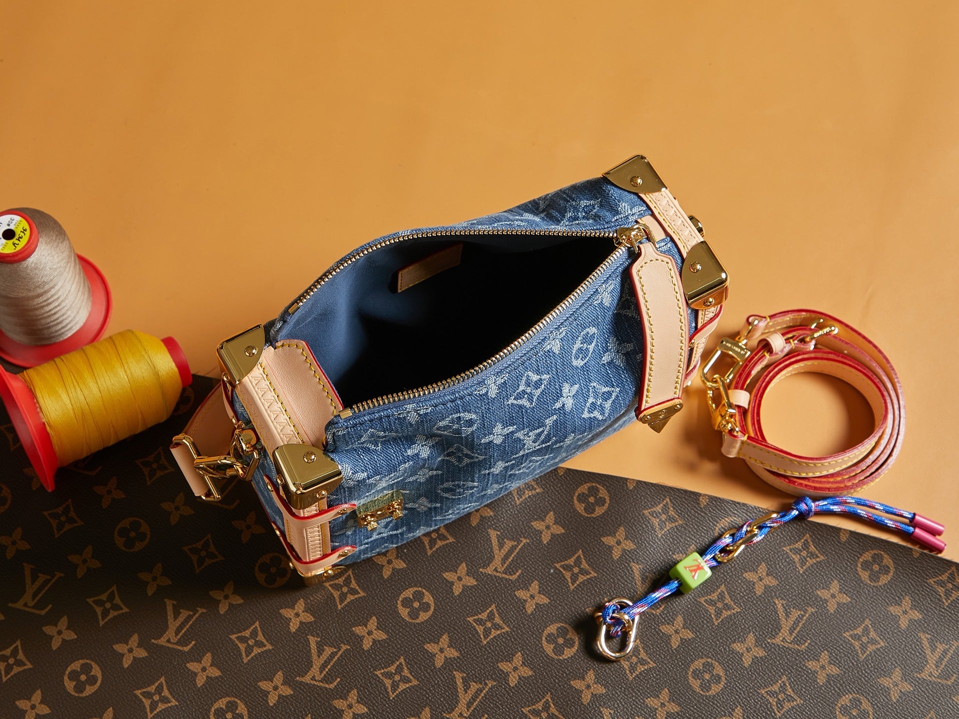 Louis Vuitton handbag open top with blue monogram canvas, tan trim, and gold zipper hardware