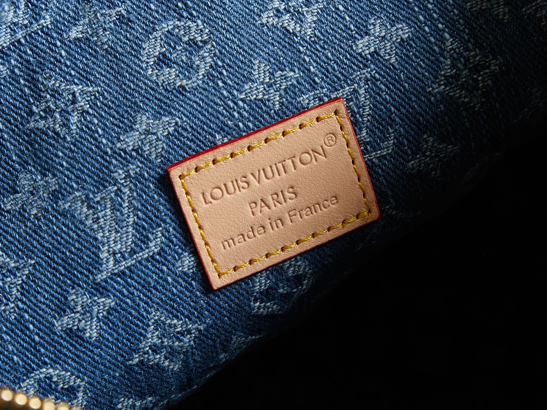 Louis Vuitton Paris leather label on blue denim with monogram texture