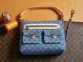 Blue denim handbag with monogram print, tan top handles, and gold-tone hardware