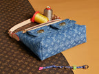 Blue denim handbag with monogram print and tan crossbody strap, gold-tone hardware
