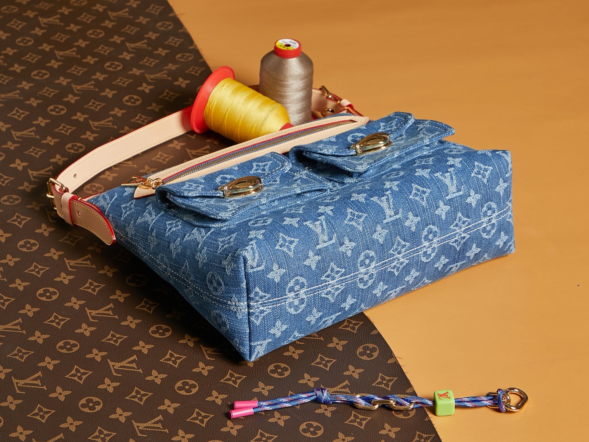 Blue denim handbag with monogram print and tan crossbody strap, gold-tone hardware