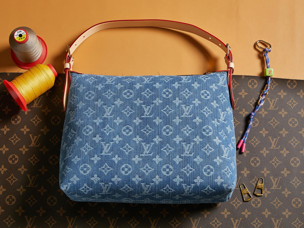 Blue denim handbag with monogram print, tan handles, and detachable key strap