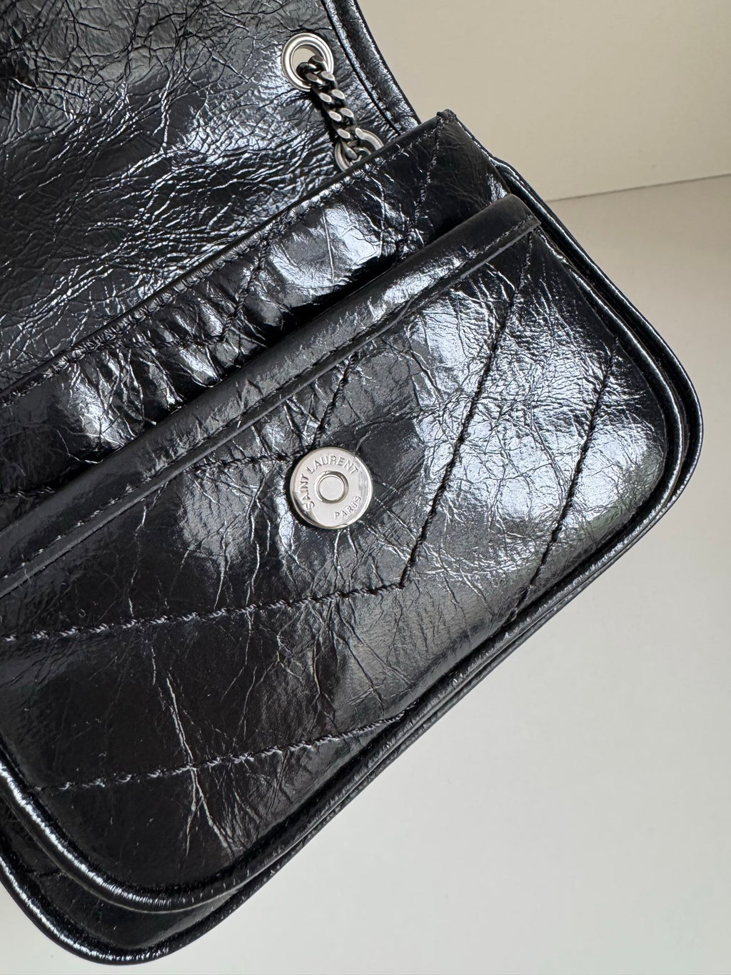 Black leather mini bag corner with snap stud and stitched flap seam