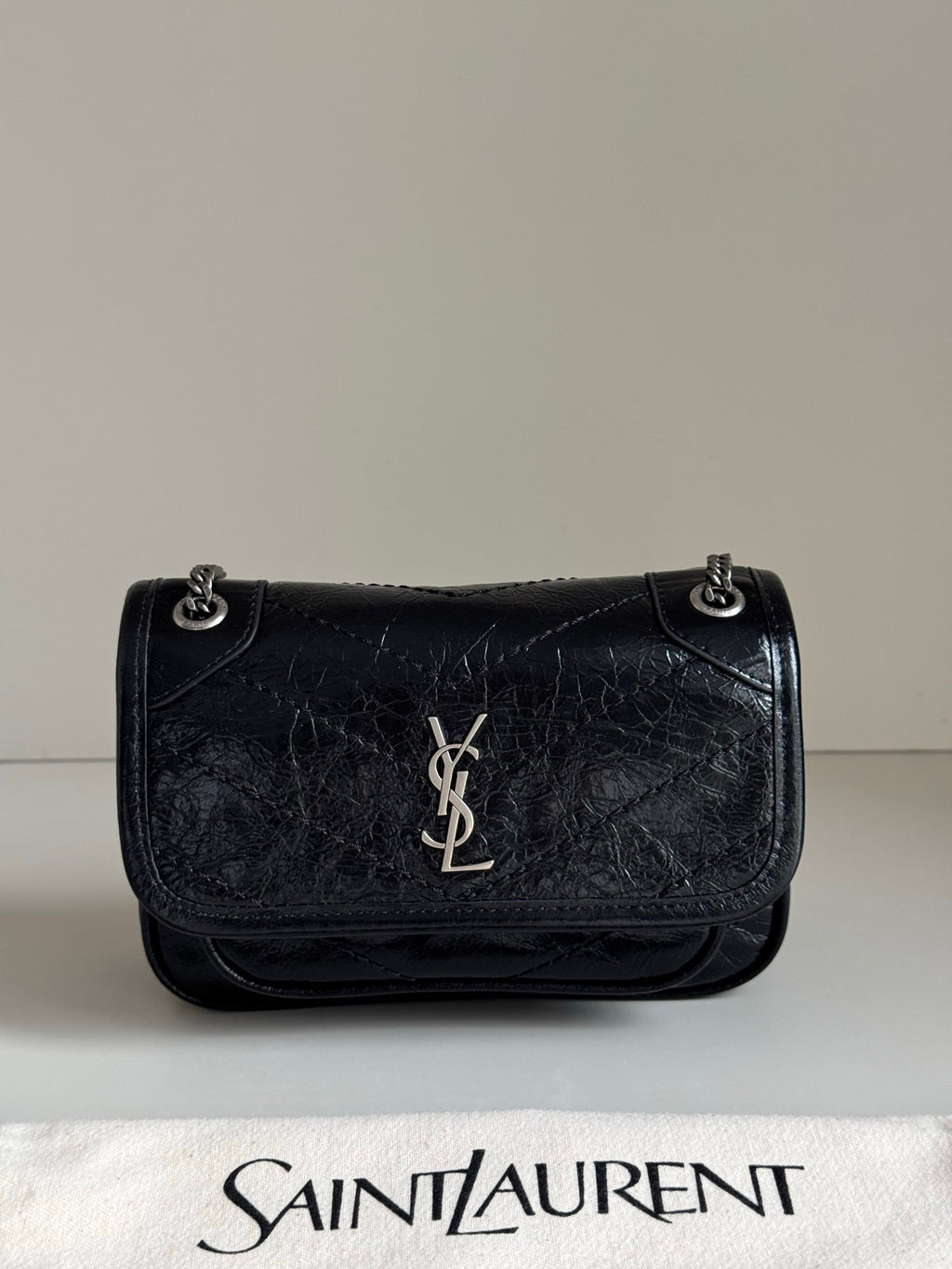 Black leather flap shoulder bag with chain strap, YSL logo, and embossed texture