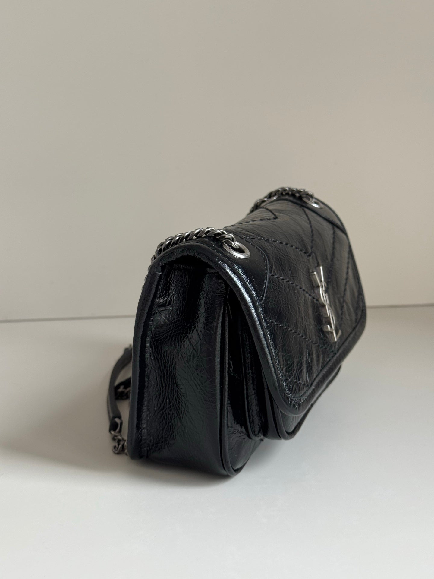 Black leather shoulder bag with chain strap and textured curved profile