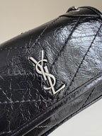 Black leather flap close-up with YSL metal logo and stitched border
