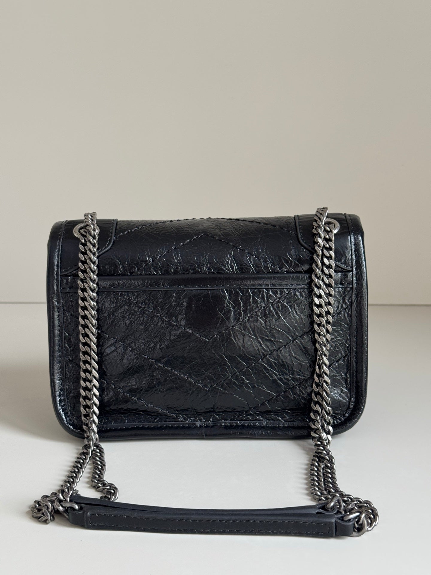 Black leather crossbody bag with flap, chain straps, and YSL front emblem