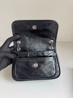 Black leather mini bag with snap front flap and chain strap hardware