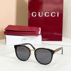Sunglasses with black frames and dark lenses, gold logo on temple