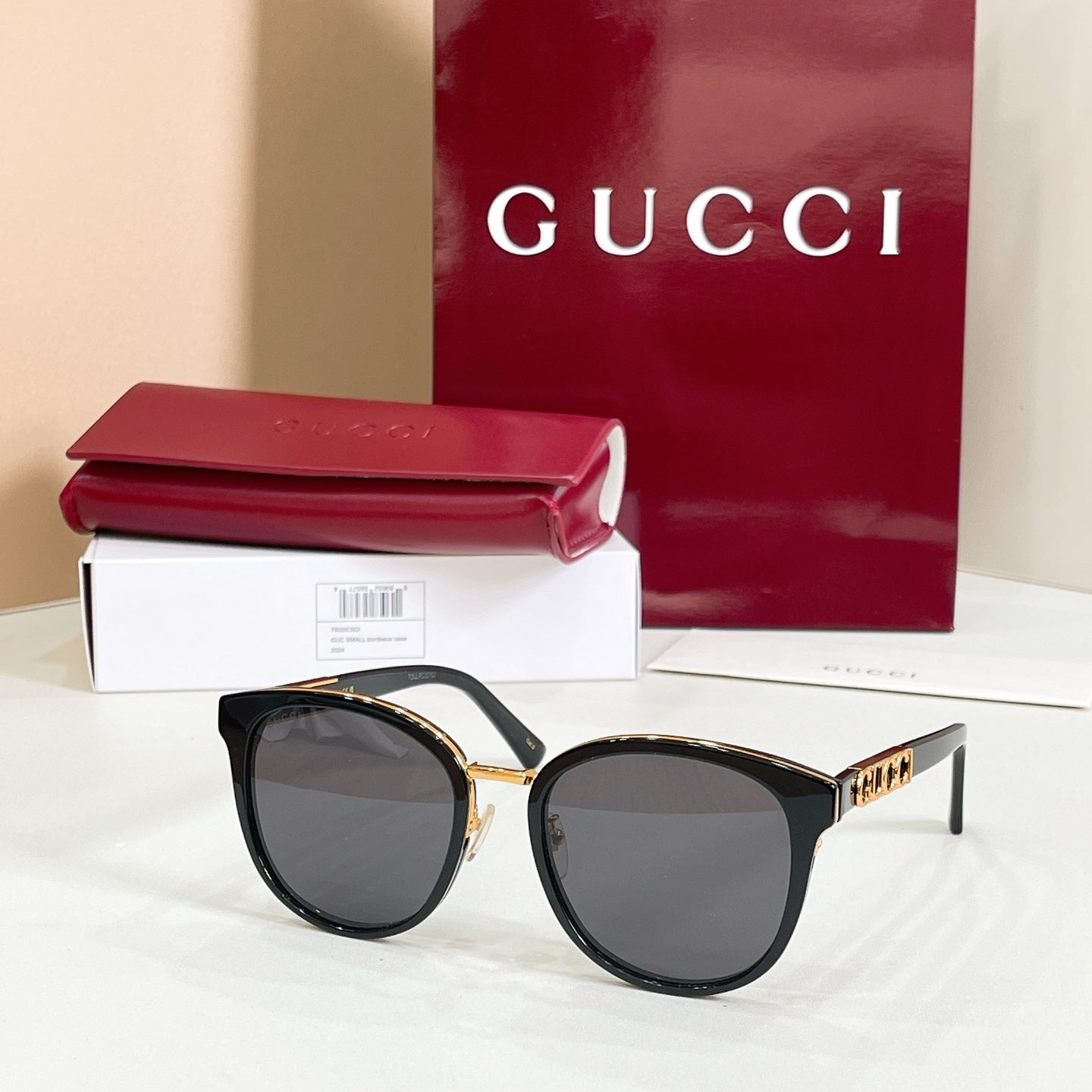 Sunglasses with black frames and dark lenses, gold logo on temple