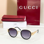 Round sunglasses with black frames, violet-tinted lenses, and gold accents