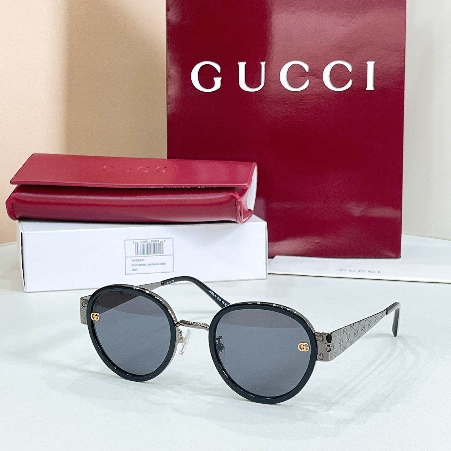 Round sunglasses with black frames, dark lenses, and gold logo details