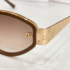 Sunglasses close-up: gold patterned temple with GG logo