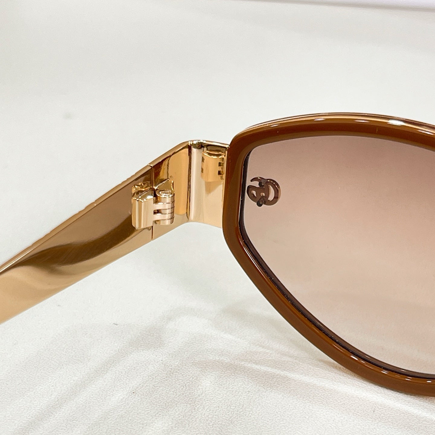 Sunglasses close-up: gold hinge and amber-tinted lens